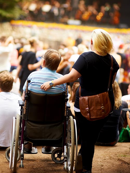 Accessibilità disabili e concerti: persona in carrozzina ad un evento con accompagnatore